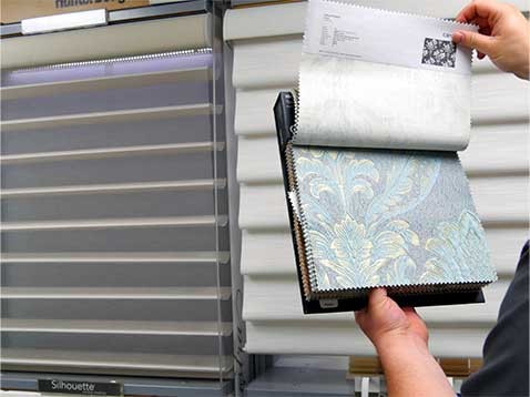 A display of two Hunter Douglas window coverings, and a booklet of fabric samples